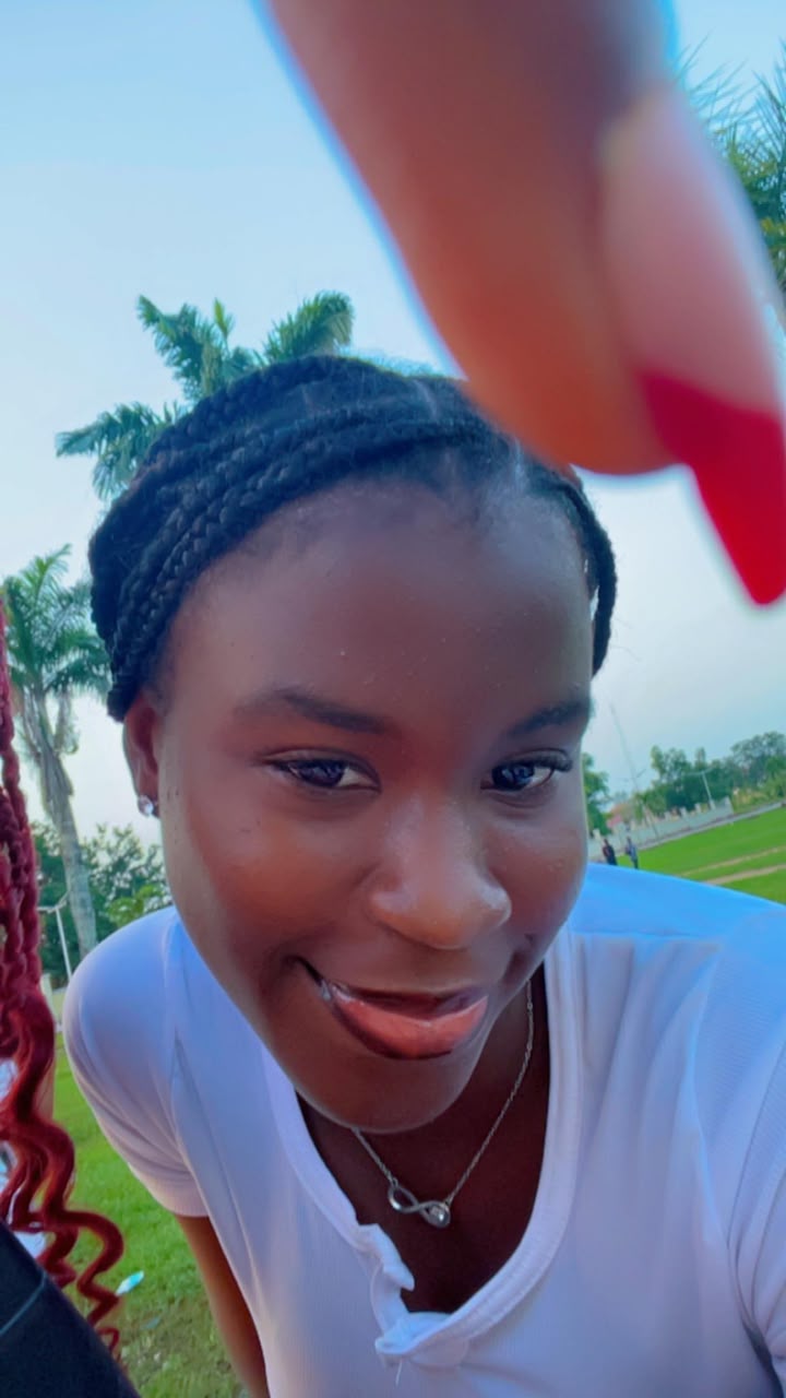 Close-up of Divine outdoors with palm trees behind her, smiling into the camera.